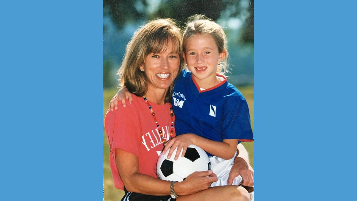 Old soccer photo of a young Darcy McFarlane holding soccer ball and posing with her mother.